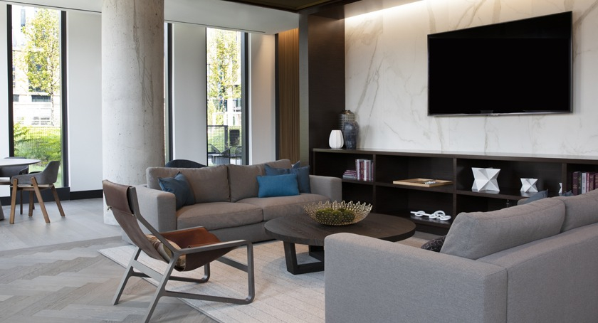 Modern resident lounge at Porte Apartments Chicago, featuring comfortable sofas, a large TV, and elegant marble-accented walls