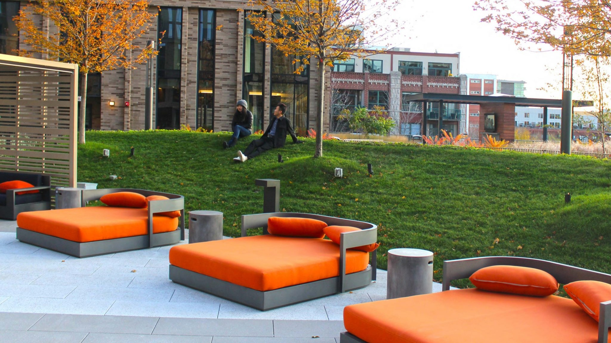 Luxurious rooftop area at Porte Apartments Chicago, offering comfortable daybeds on a lush green lawn, surrounded by modern buildings