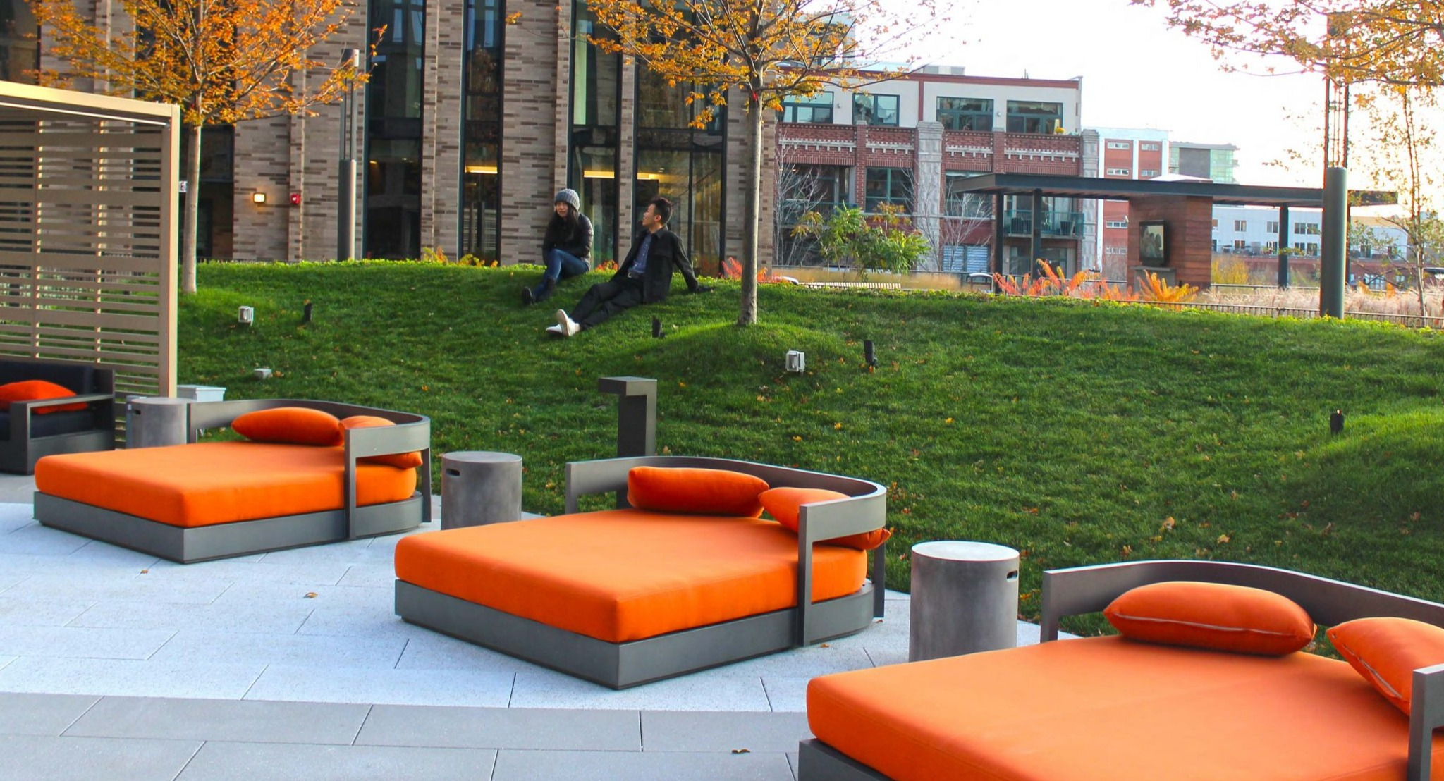 Luxurious rooftop area at Porte Apartments Chicago, offering comfortable daybeds on a lush green lawn, surrounded by modern buildings