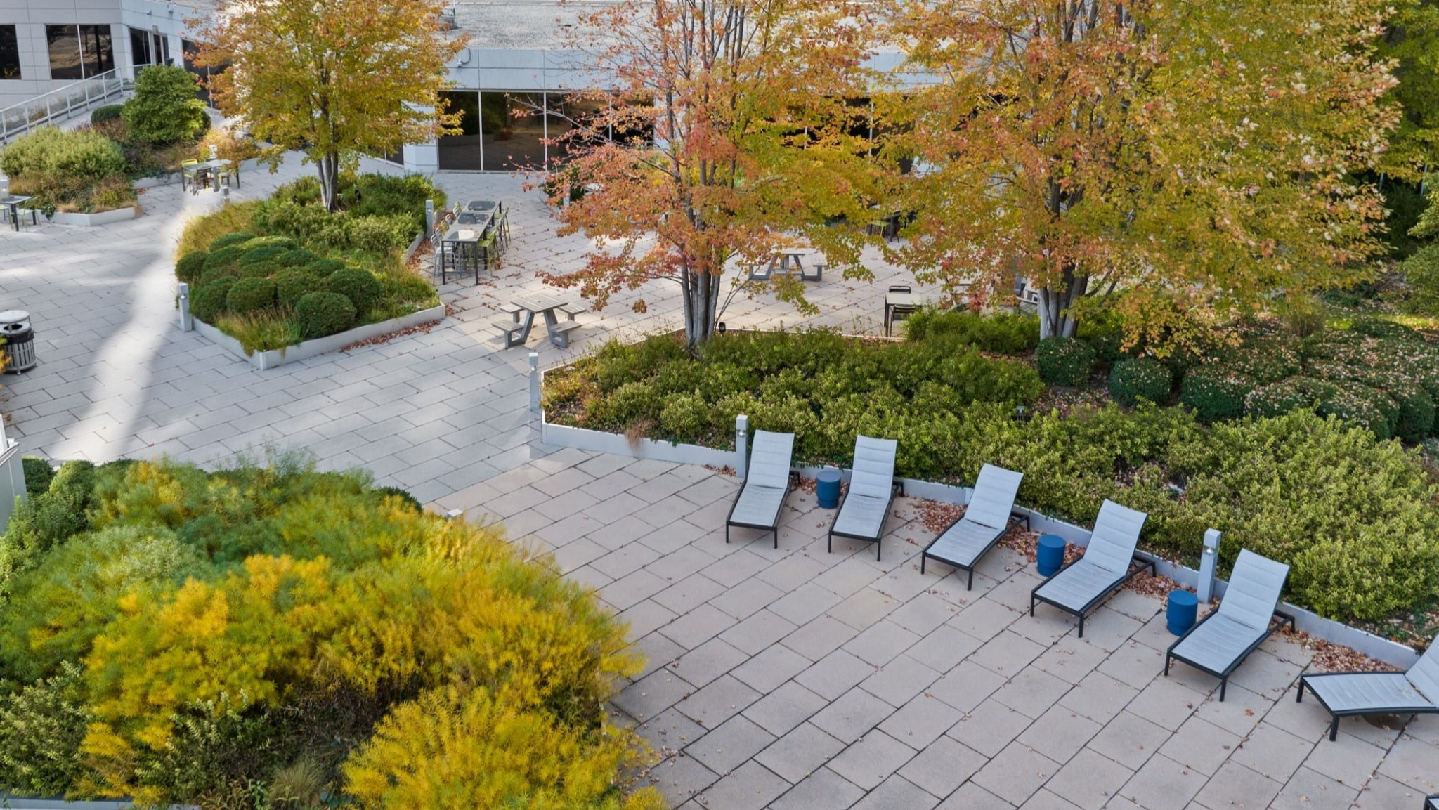 Expansive landscaped courtyard at Presidential Towers Chicago featuring trees, greenery, paved paths, picnic tables, and sun-lounger chairs for relaxing