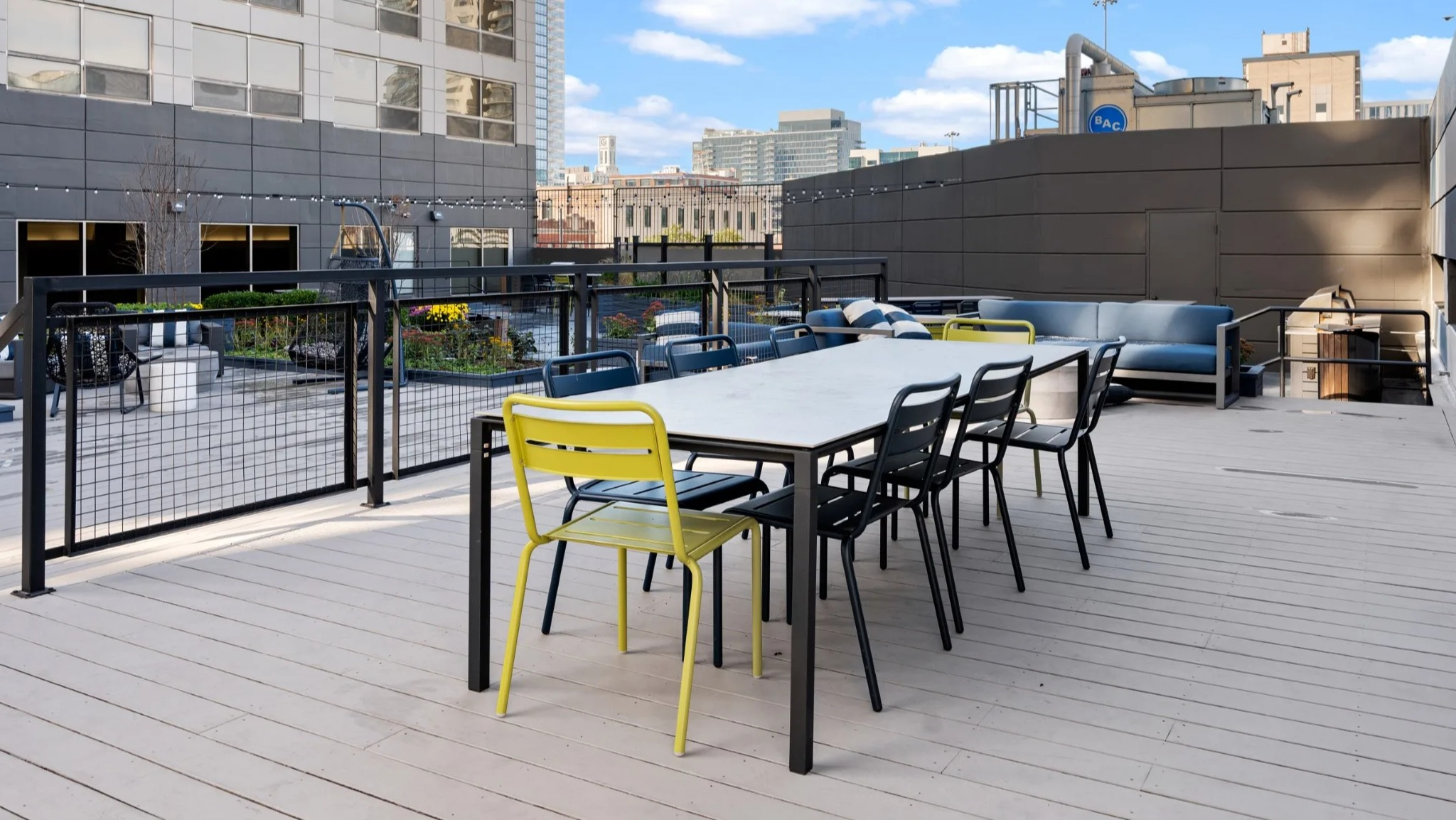Rooftop dining terrace at Presidential Towers Chicago with a long table, mixed chairs, rail lighting, and skyline views ideal for outdoor gatherings