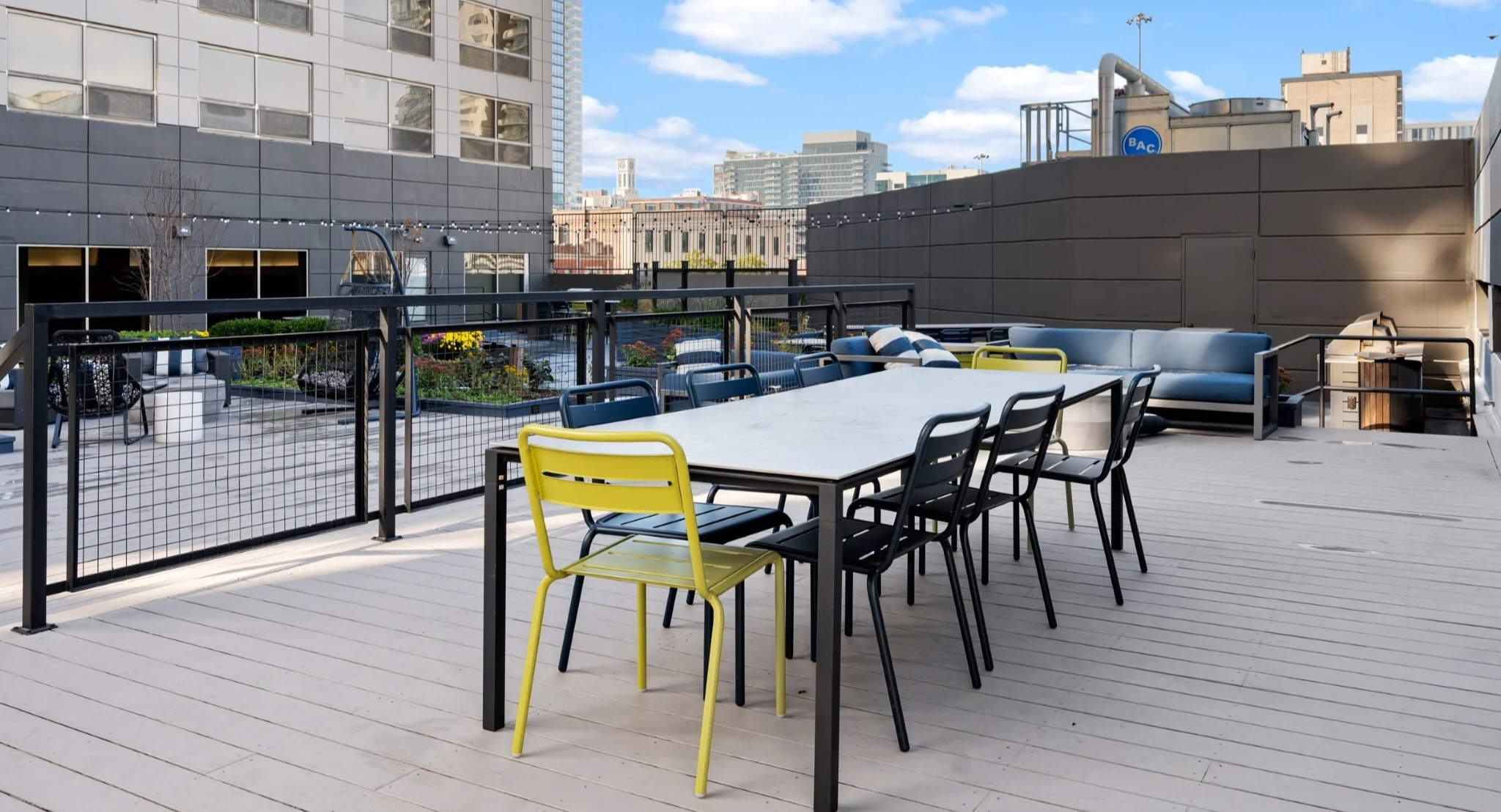 Rooftop dining terrace at Presidential Towers Chicago with a long table, mixed chairs, rail lighting, and skyline views ideal for outdoor gatherings