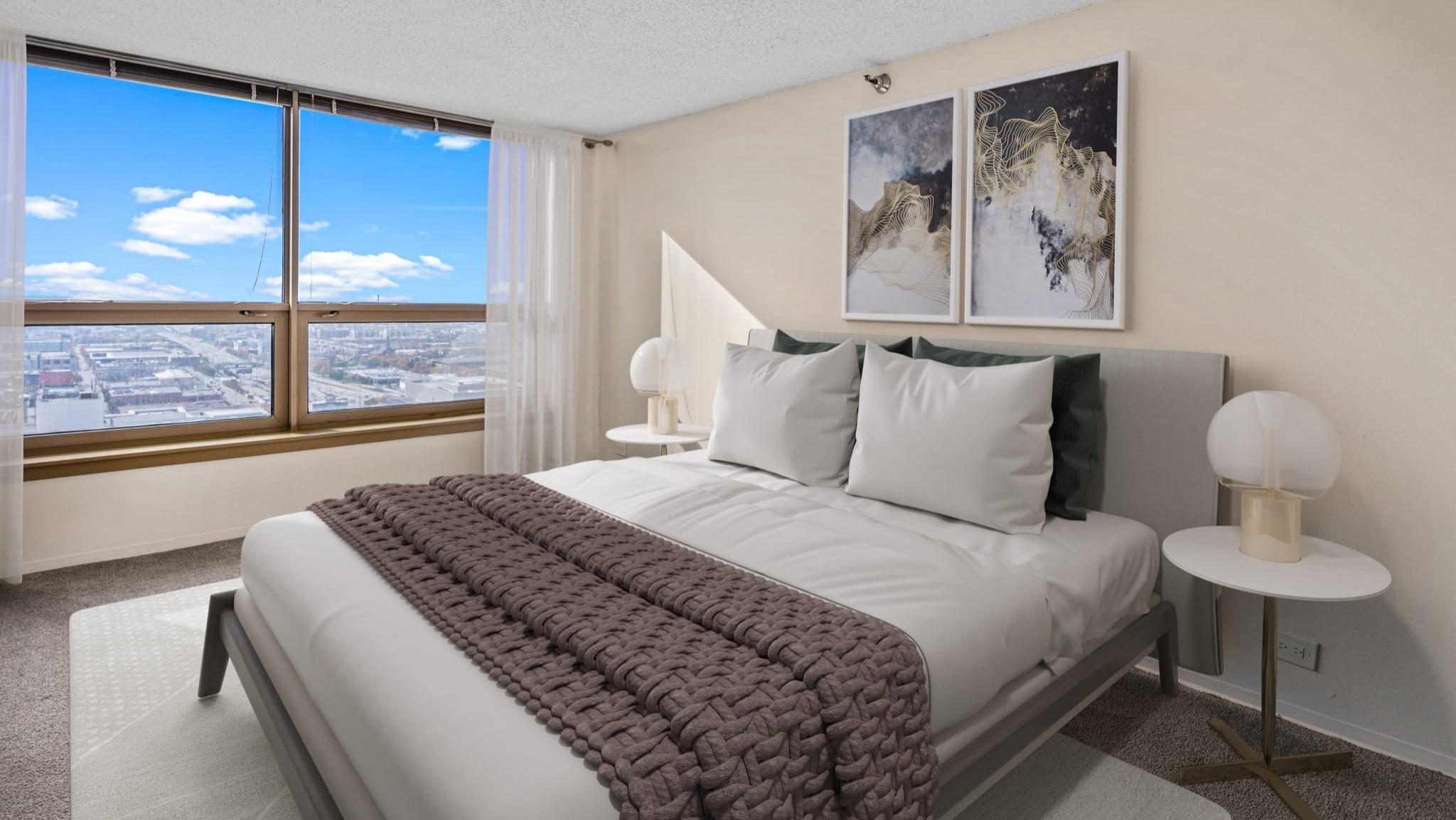 Bright bedroom with large window, skyline view, neutral decor, and modern artwork at Presidential Towers apartments in Chicago