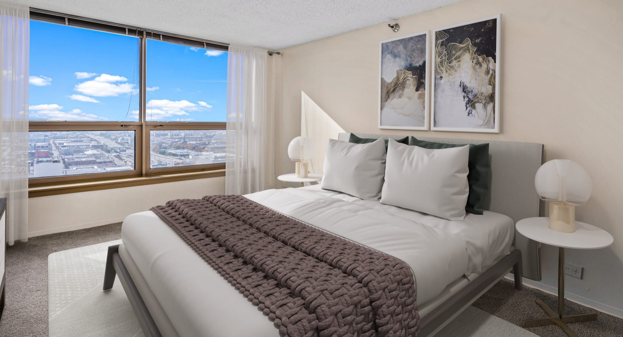 Bright bedroom with large window, skyline view, neutral decor, and modern artwork at Presidential Towers apartments in Chicago