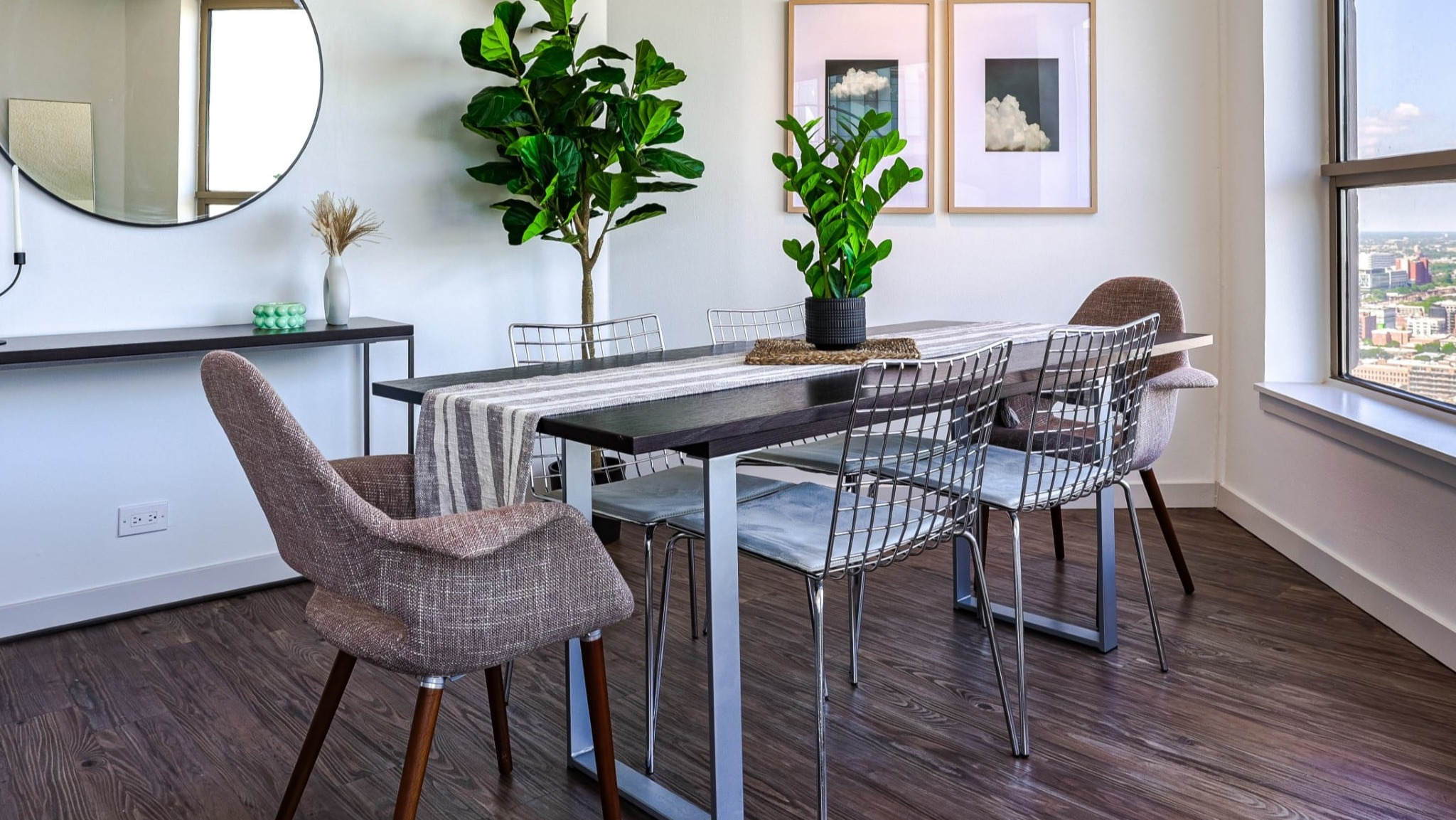 Bright dining nook at Presidential Towers in Chicago featuring a six-seat table, modern chairs, wall mirror, and floor-to-ceiling windows with city views