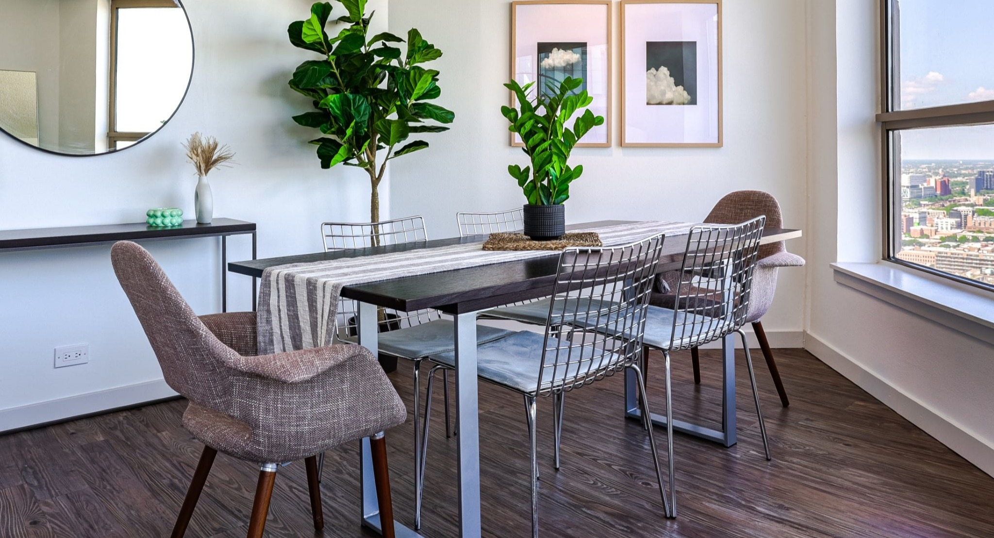 Bright dining nook at Presidential Towers in Chicago featuring a six-seat table, modern chairs, wall mirror, and floor-to-ceiling windows with city views