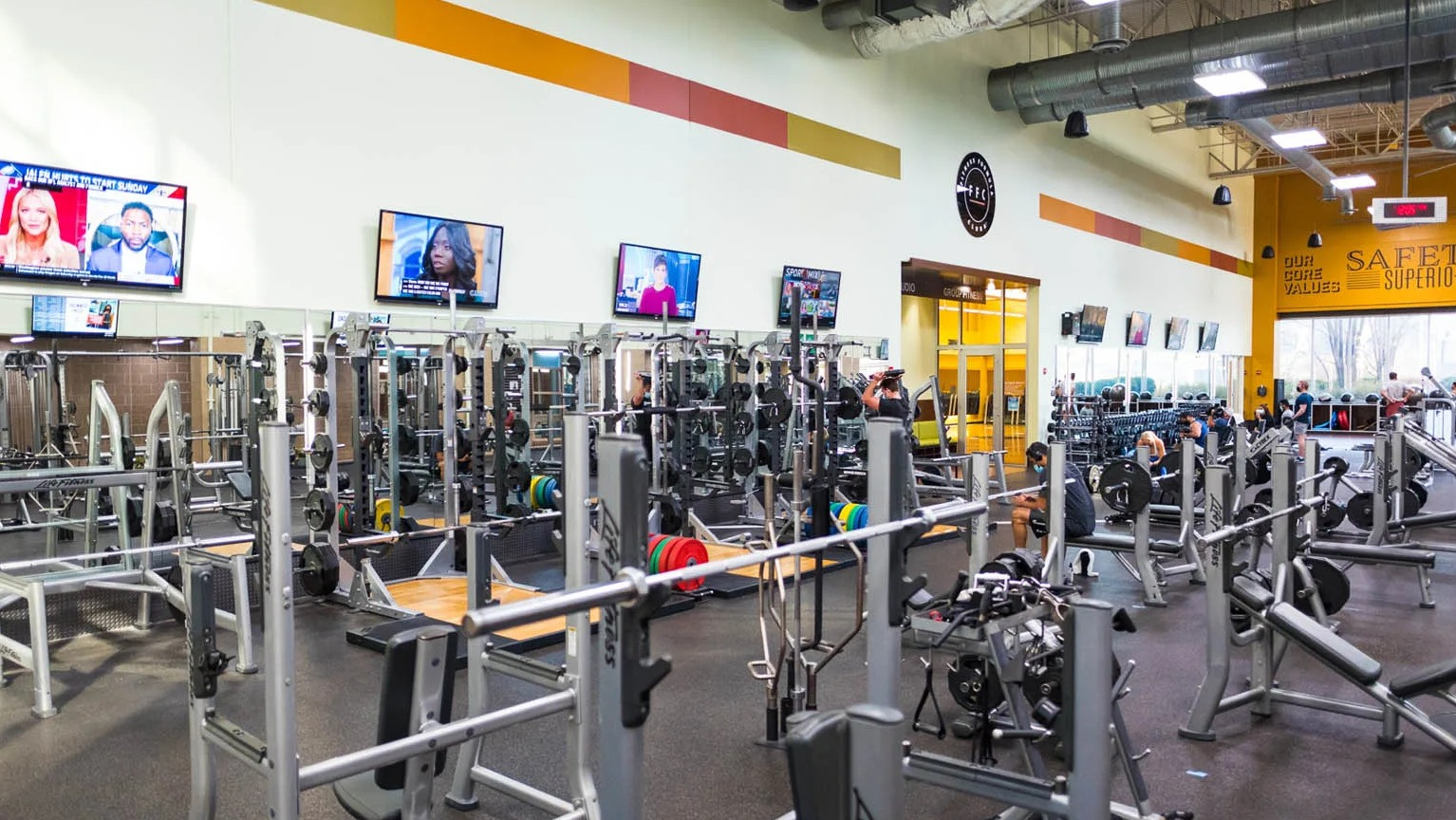 Spacious weights room with benches, racks, mirrors, and TVs at the Presidential Towers apartment fitness center in Chicago