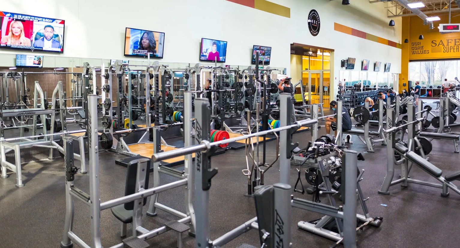 Spacious weights room with benches, racks, mirrors, and TVs at the Presidential Towers apartment fitness center in Chicago