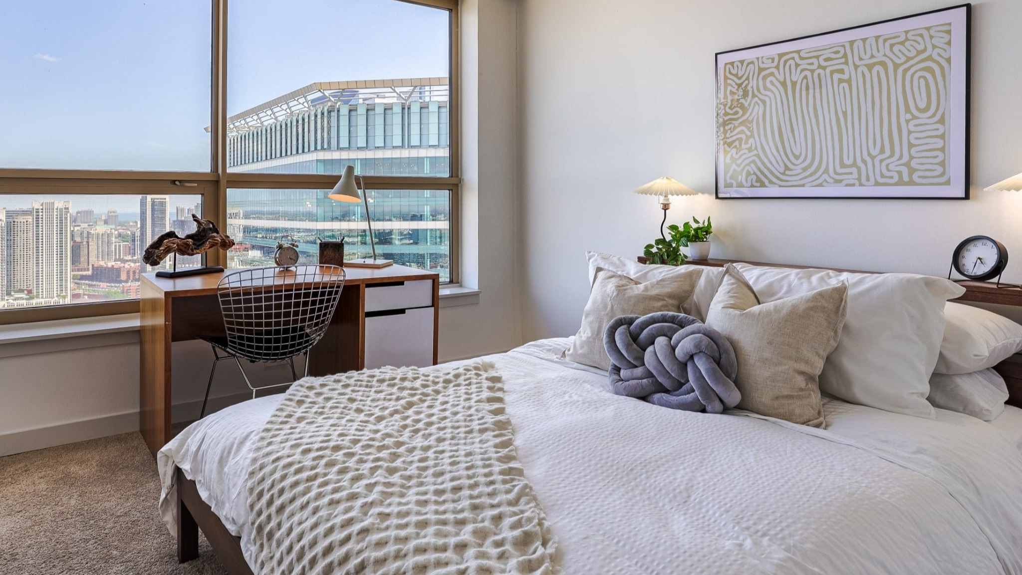 Peaceful bedroom at Presidential Towers in Chicago featuring a comfy bed, soft bedding, night lamps, and a windowed desk ideal for work with skyline views