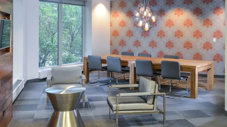 Resident lounge with long conference table, modern lighting, and wallpaper accents at Presidential Towers apartments in Chicago