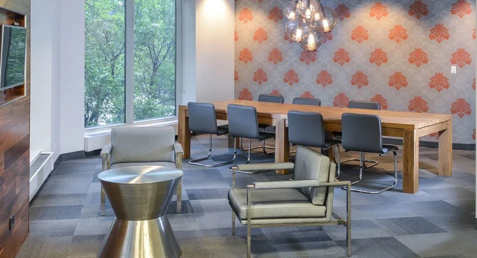 Resident lounge with long conference table, modern lighting, and wallpaper accents at Presidential Towers apartments in Chicago