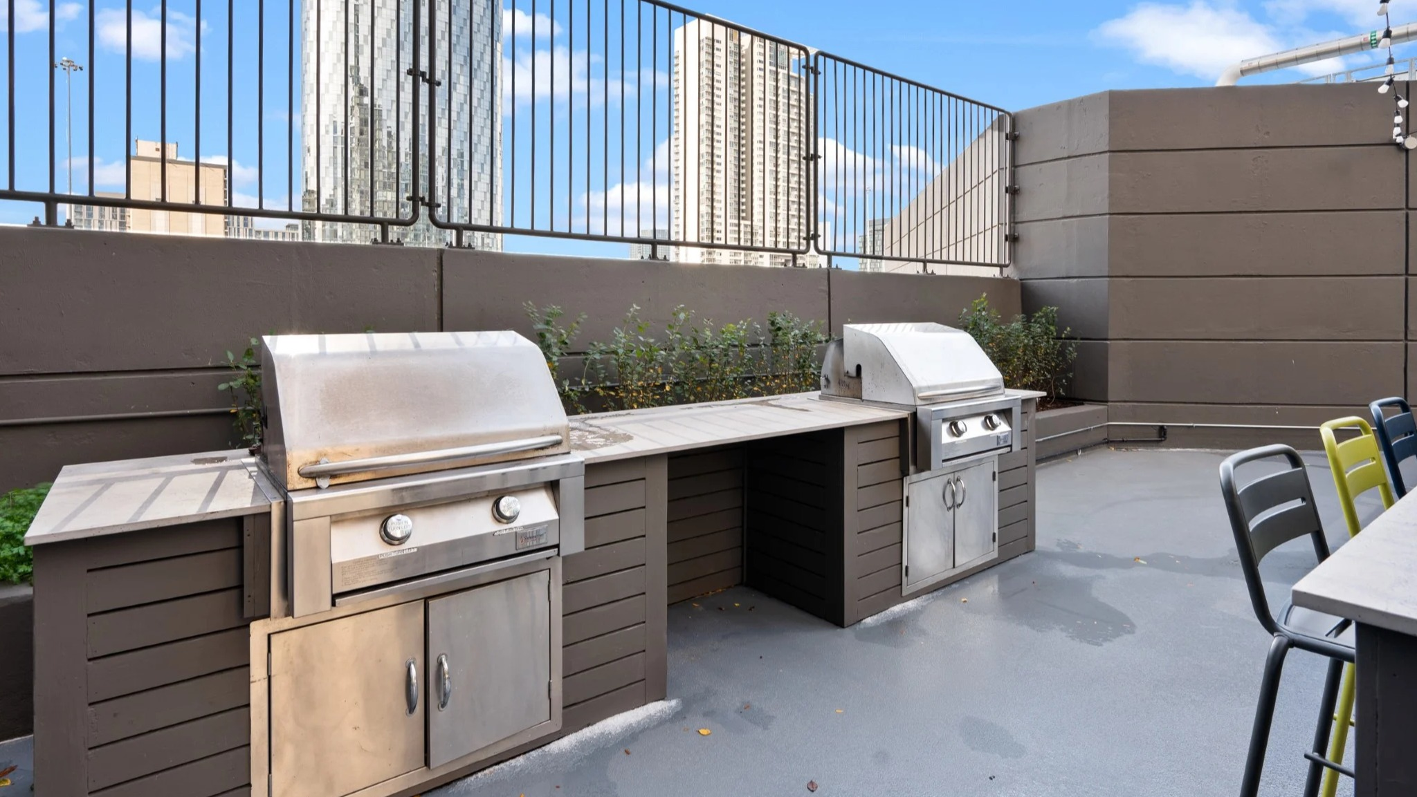 Rooftop terrace with built-in grilling stations, bar seating, planters, and city views at Presidential Towers apartments in Chicago