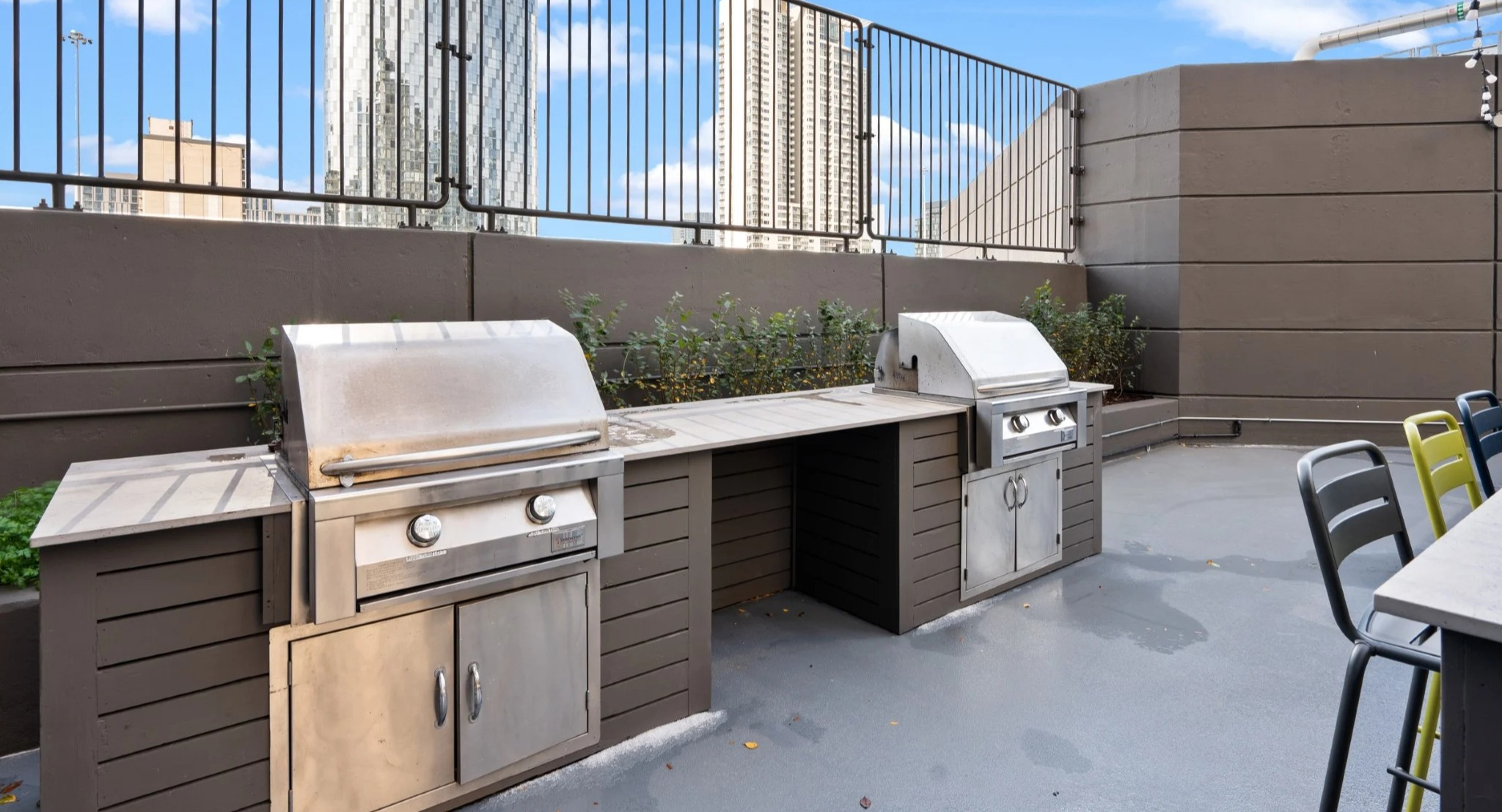Rooftop terrace with built-in grilling stations, bar seating, planters, and city views at Presidential Towers apartments in Chicago