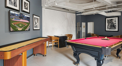 Lively game room at Randolph Tower City Apartments in Chicago, featuring a shuffleboard table, pool table, and flat-screen TV