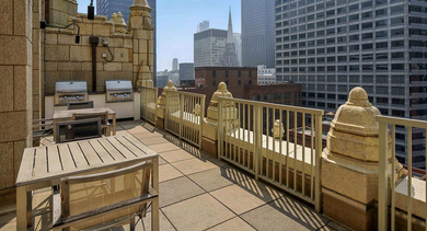 Scenic rooftop grilling area at Randolph Tower City Apartments in Chicago, featuring multiple grills, dining tables, and city skyline views
