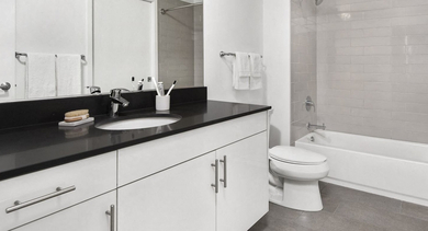 Contemporary apartment bathroom at Reside on Green Street in Chicago, featuring a vanity with dark countertop, and a tub-shower combo with subway tiles