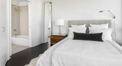 Bright apartment bedroom at Reside on Green Street in Chicago, featuring a comfortable bed, large window, and ensuite bathroom access