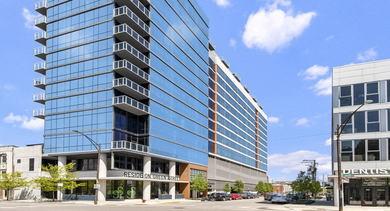 Modern glass building exterior of Reside on Green Street in Chicago, showcasing its contemporary architecture against a blue sky