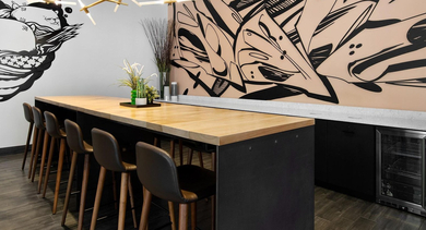 Trendy co-working space with a long communal table, comfortable stools, and urban graffiti-style wall art at Reside on Green Street in Chicago