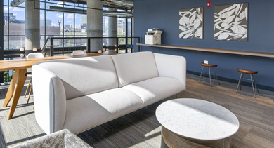 Spacious co-working lounge with a large sofa, work tables, and plenty of natural light, perfect for productivity at Reside on Green Street in Chicago