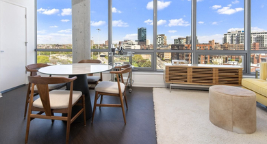 Open dining and living area at Reside on Green Street in Chicago, featuring a round dining table, cozy sofa, and large windows with city views