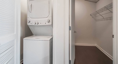 Convenient in-unit stacked washer and dryer at Reside on Green Street in Chicago, adjacent to a spacious closet