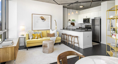 Vibrant open-concept living room and kitchen with a yellow sofa, modern furniture, and a kitchen island at Reside on Green Street in Chicago