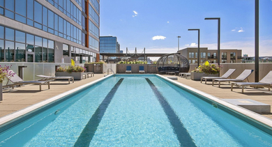 Sparkling outdoor lap pool surrounded by lounge chairs and planters, offering a sunny escape at Reside on Green Street in Chicago