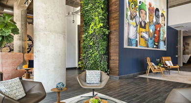 Stylish resident lounge featuring a striking vertical garden, modern seating, and a large colorful mural at Reside on Green Street in Chicago