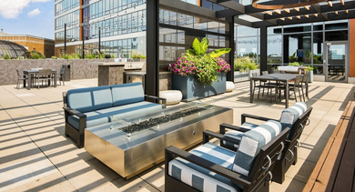 Inviting rooftop lounge with a modern fire pit, comfortable seating, and planters under a pergola at Reside on Green Street in Chicago