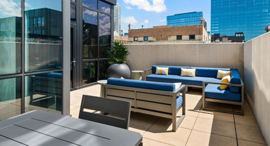 Modern rooftop lounge with vibrant blue sofas, outdoor tables, and views of the surrounding city at Reside on Green Street in Chicago