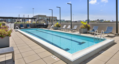 Sunny rooftop pool area with lounge chairs and potted plants, perfect for relaxation at Reside on Green Street in Chicago