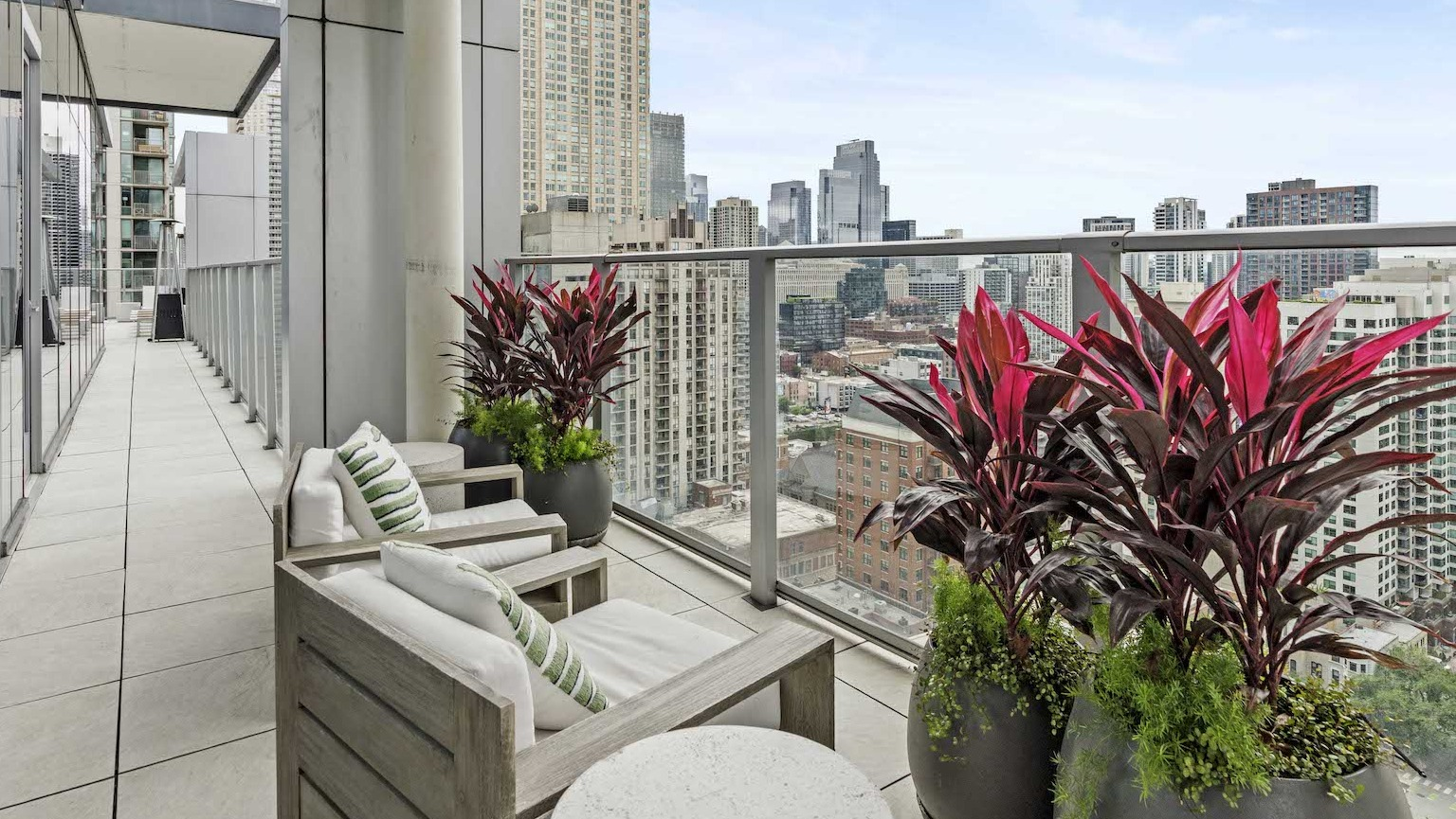 Private balcony with comfortable seating, vibrant plants, and expansive views of the Chicago cityscape at Residences at 8 East Huron in Chicago