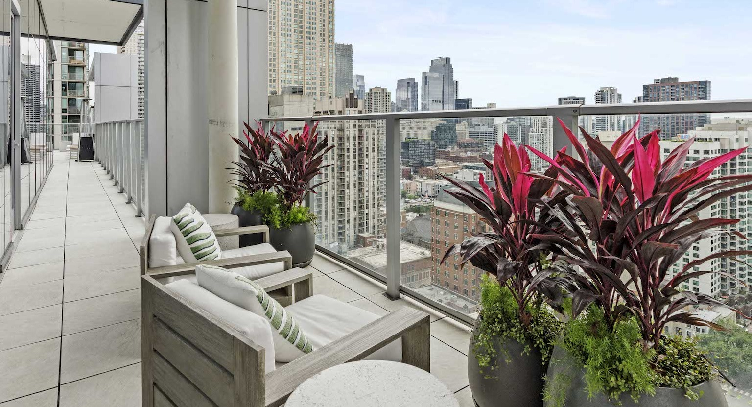 Private balcony with comfortable seating, vibrant plants, and expansive views of the Chicago cityscape at Residences at 8 East Huron in Chicago