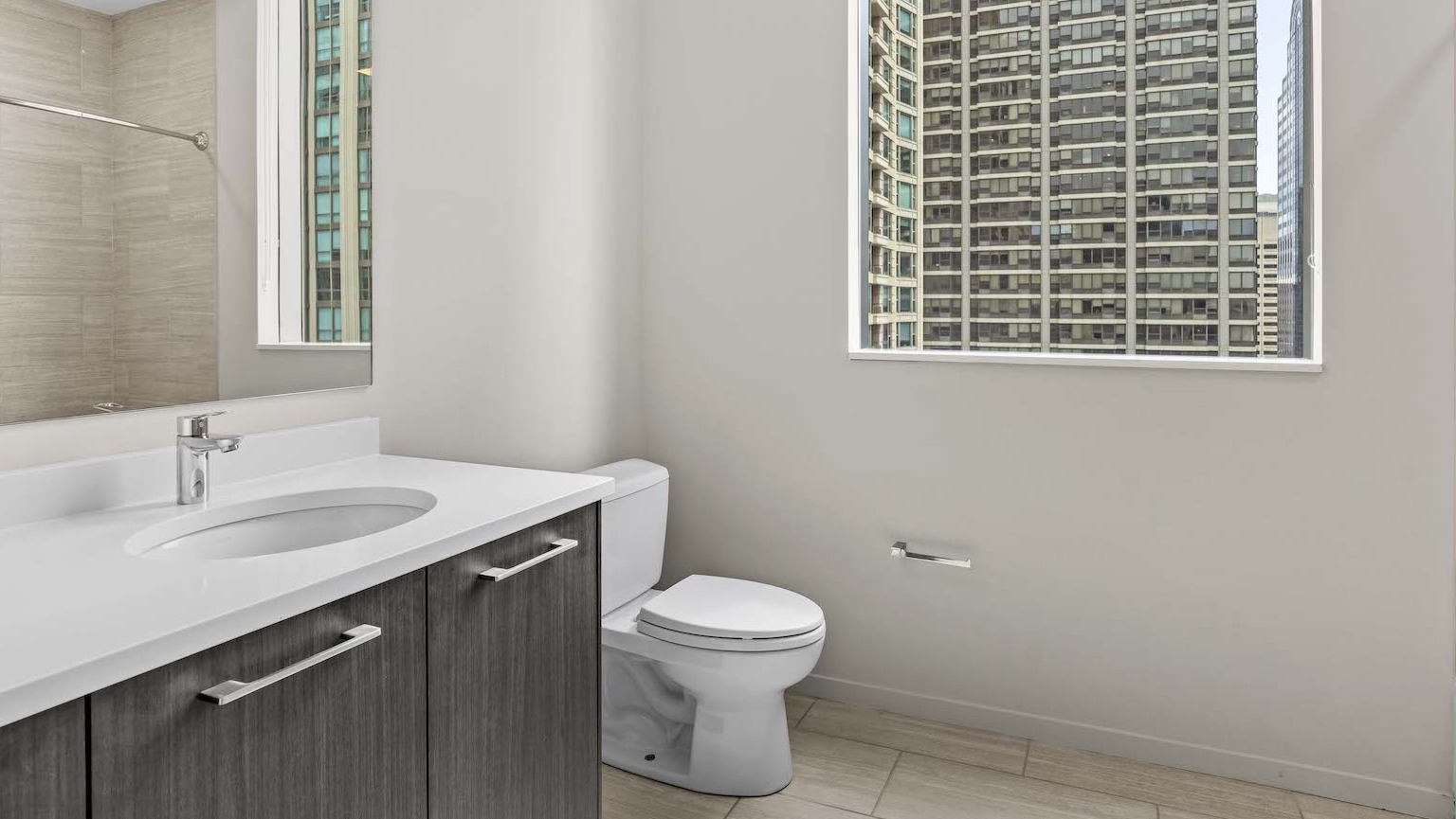 Contemporary bathroom with a modern vanity, large mirror, and a bathtub with tiled walls at Residences at 8 East Huron in Chicago