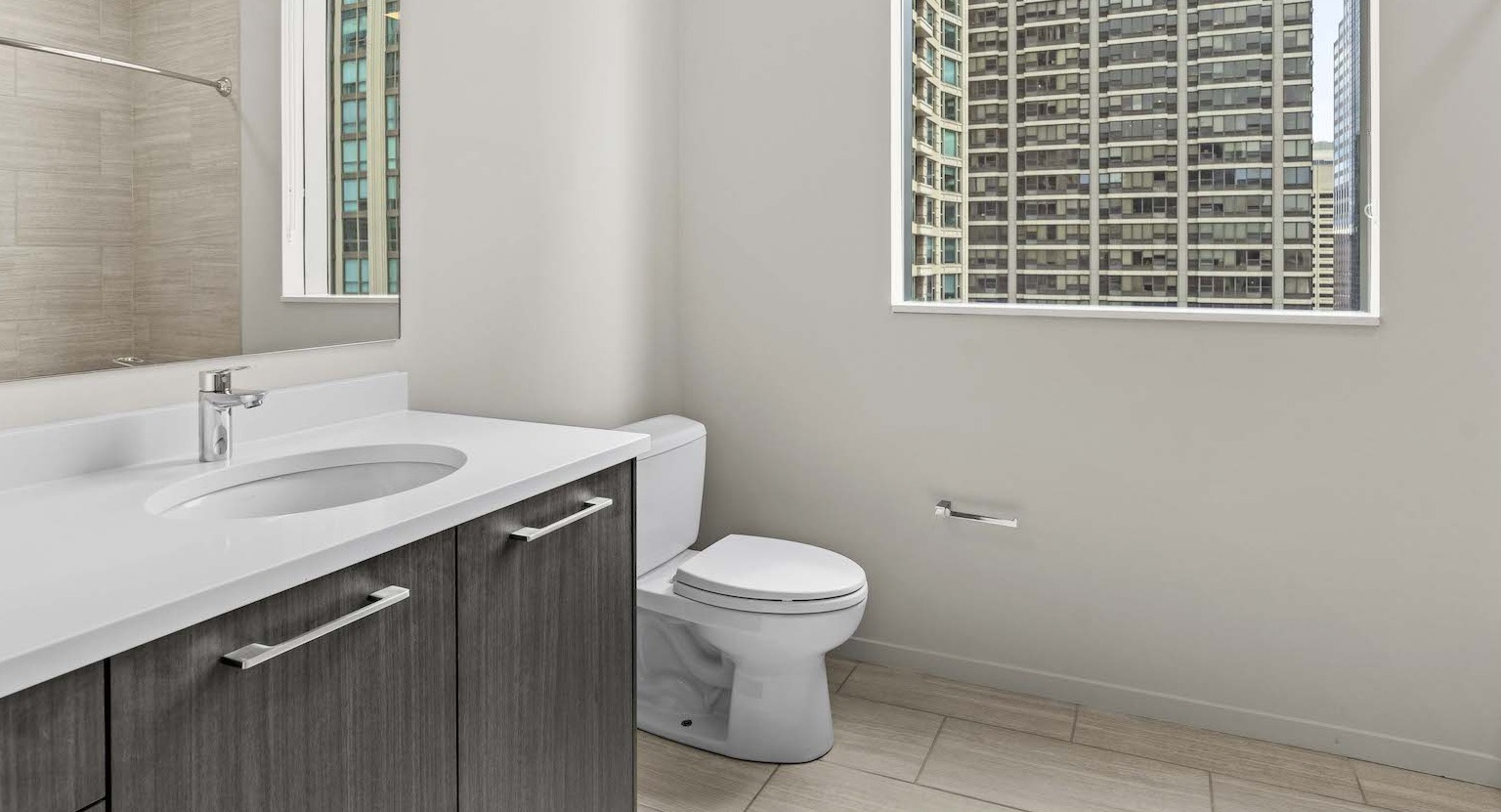 Contemporary bathroom with a modern vanity, large mirror, and a bathtub with tiled walls at Residences at 8 East Huron in Chicago