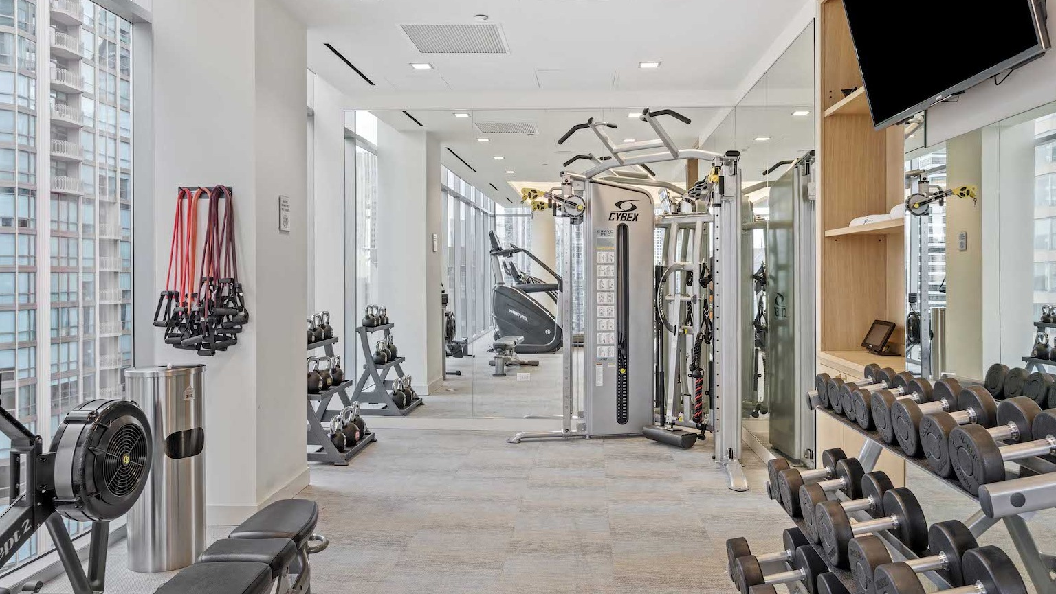 State-of-the-art fitness center with free weights, strength training machines, and city views at Residences at 8 East Huron in Chicago