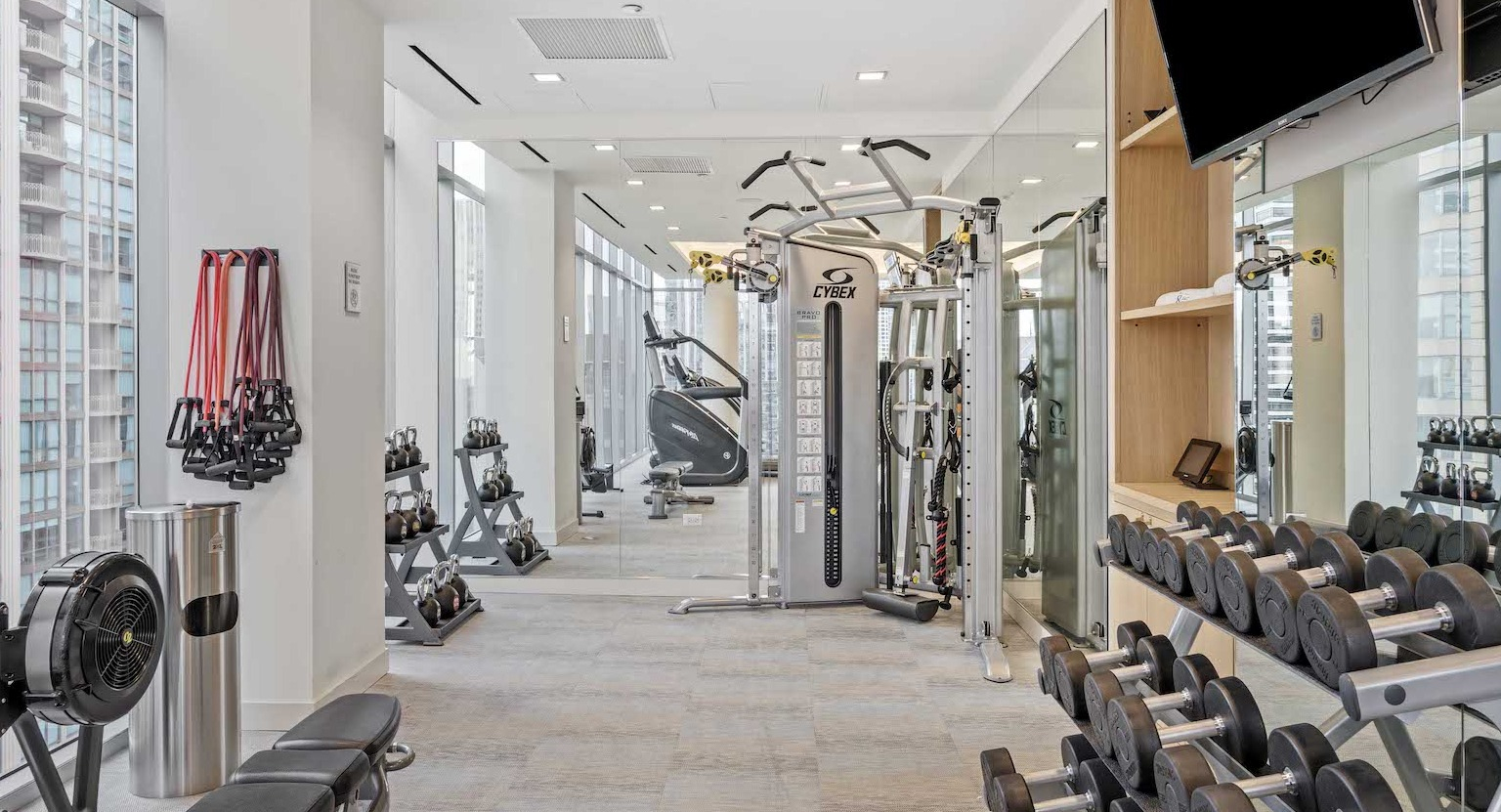 State-of-the-art fitness center with free weights, strength training machines, and city views at Residences at 8 East Huron in Chicago