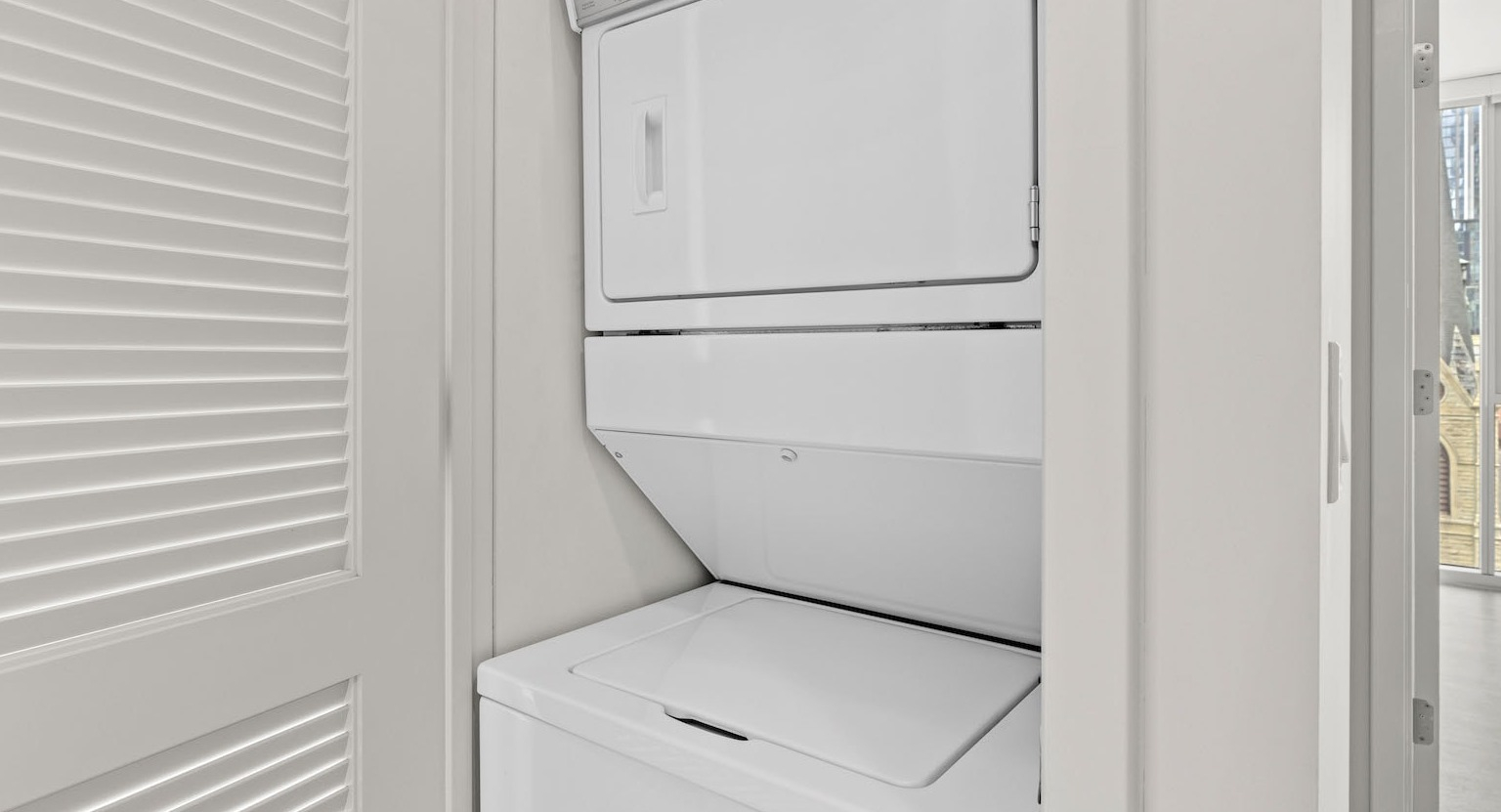 Convenient in-unit stacked washer and dryer unit discreetly placed in a closet at Residences at 8 East Huron in Chicago