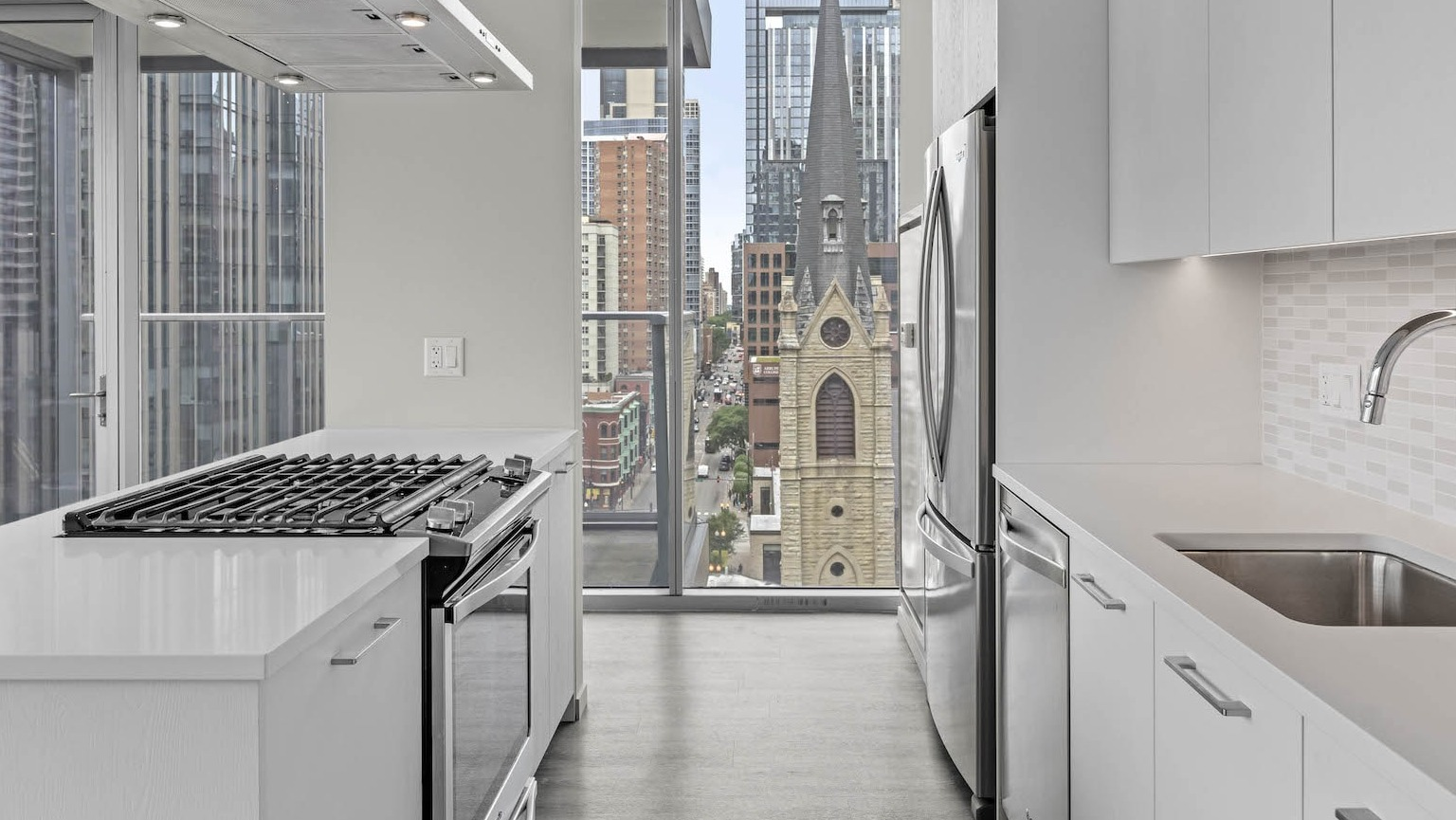Contemporary kitchen featuring white cabinets, stainless steel appliances, and a unique view of a historic church at Residences at 8 East Huron in Chicago