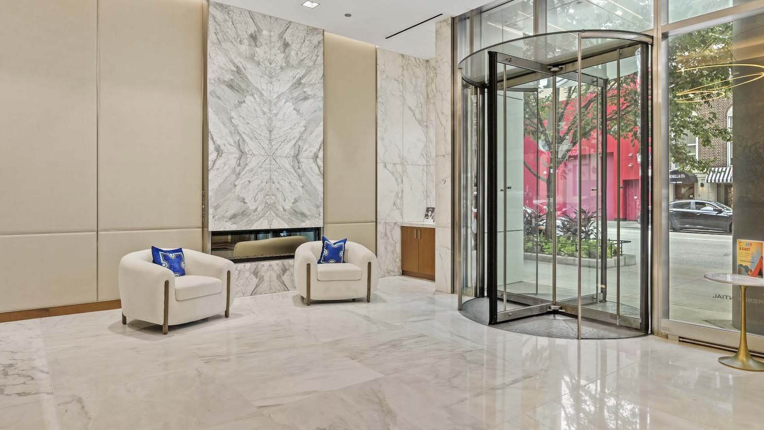 Elegant lobby entrance with marble floors, comfortable seating, a fireplace, and a revolving door at Residences at 8 East Huron in Chicago