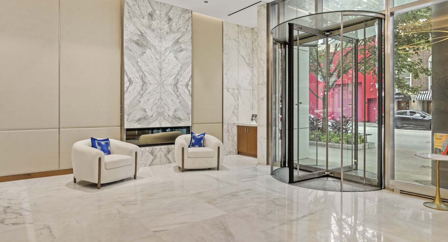 Elegant lobby entrance with marble floors, comfortable seating, a fireplace, and a revolving door at Residences at 8 East Huron in Chicago