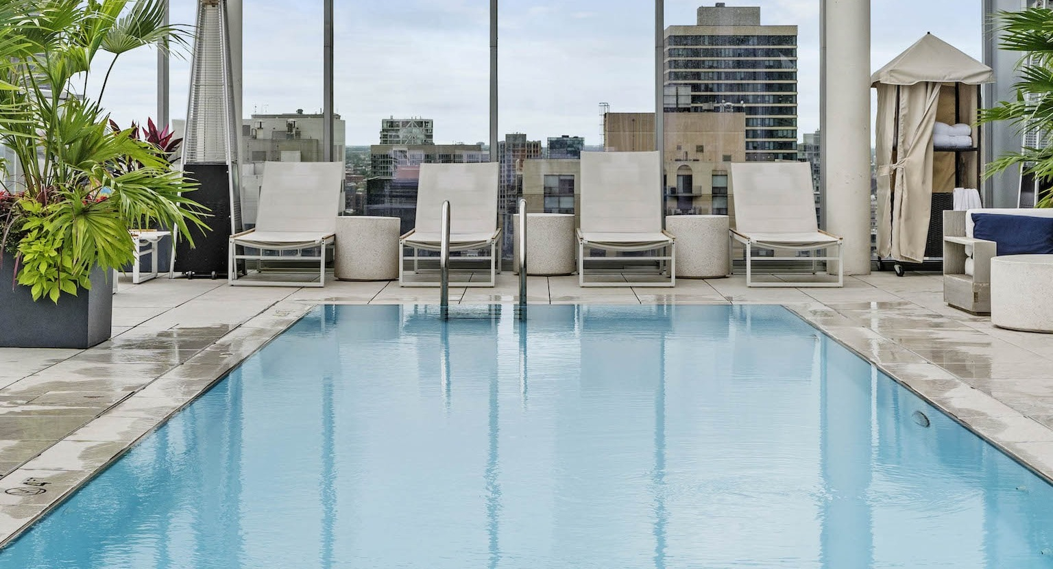 Serene poolside lounge area with comfortable reclining chairs and beautiful city backdrop at Residences at 8 East Huron in Chicago