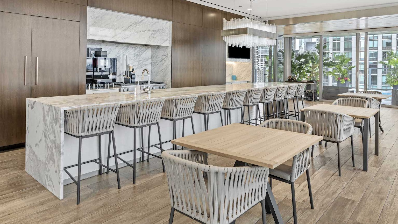 Luxurious private dining room with a long marble island, bar seating, and a modern kitchen at Residences at 8 East Huron in Chicago