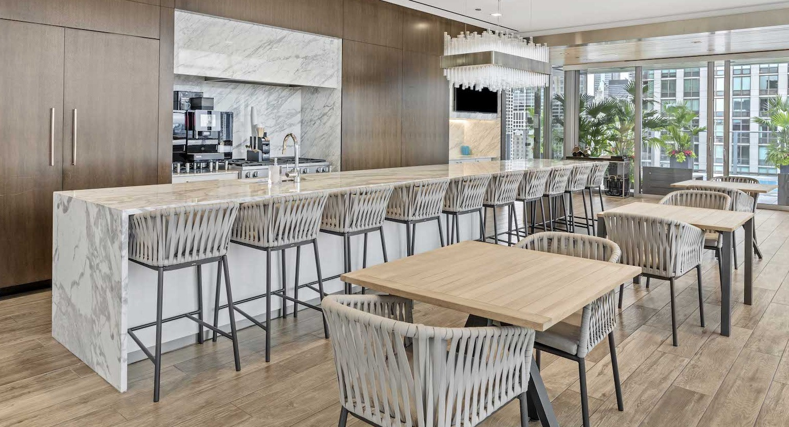 Luxurious private dining room with a long marble island, bar seating, and a modern kitchen at Residences at 8 East Huron in Chicago