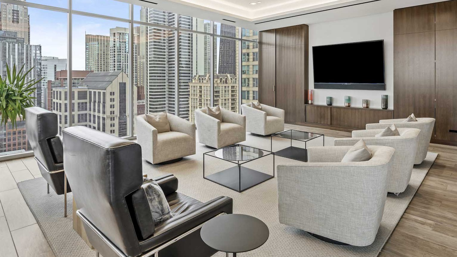 Elegant resident lounge with comfortable armchairs, coffee tables, and a large flat-screen TV at Residences at 8 East Huron in Chicago