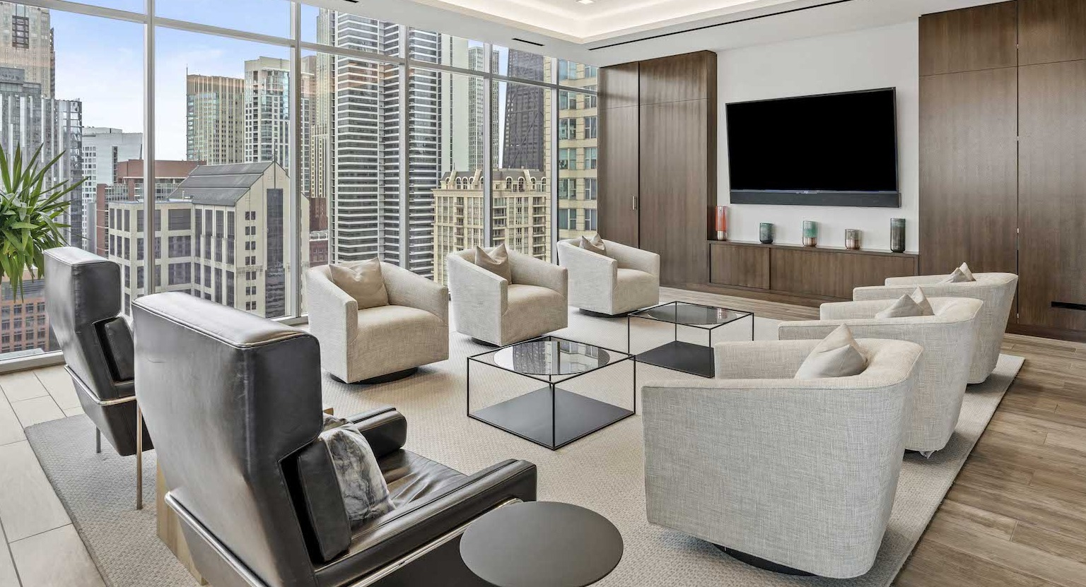 Elegant resident lounge with comfortable armchairs, coffee tables, and a large flat-screen TV at Residences at 8 East Huron in Chicago