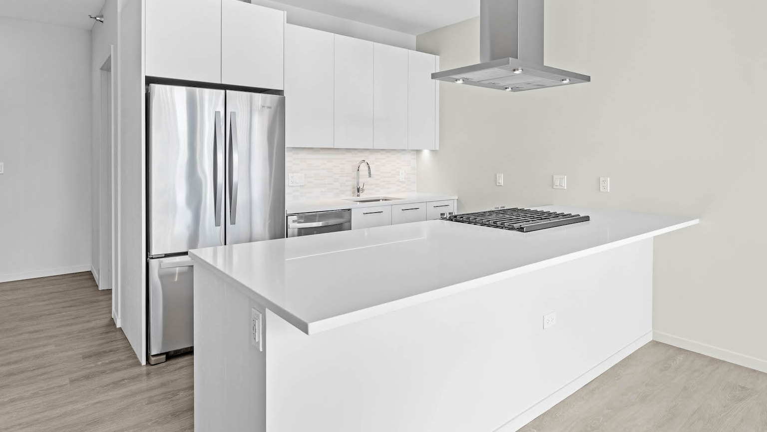 Bright, minimalist white kitchen with an island, stainless steel appliances, and a sleek modern design at Residences at 8 East Huron in Chicago