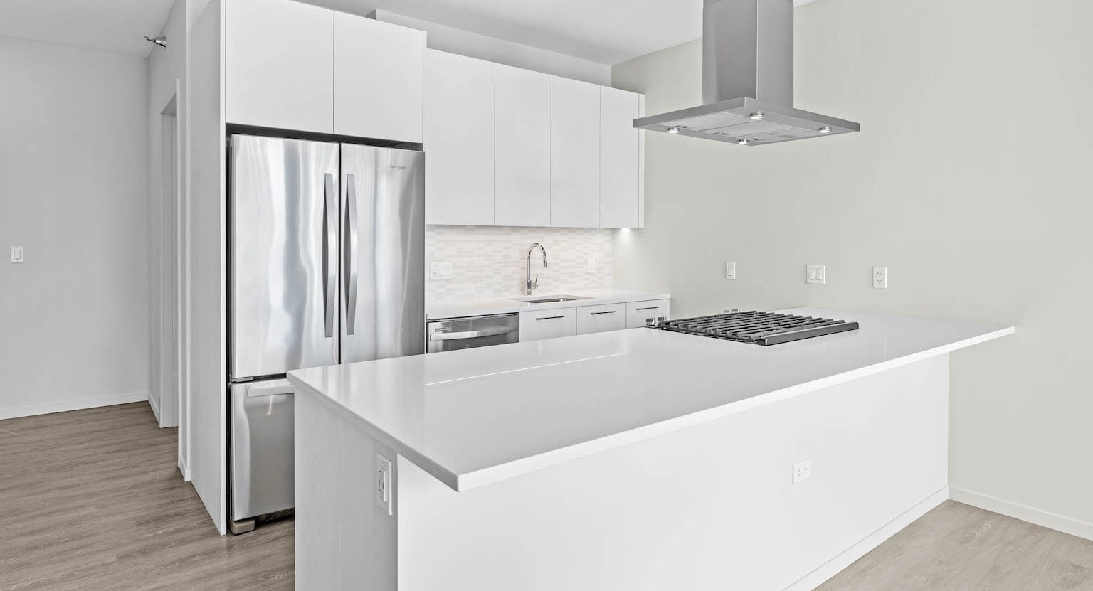 Bright, minimalist white kitchen with an island, stainless steel appliances, and a sleek modern design at Residences at 8 East Huron in Chicago