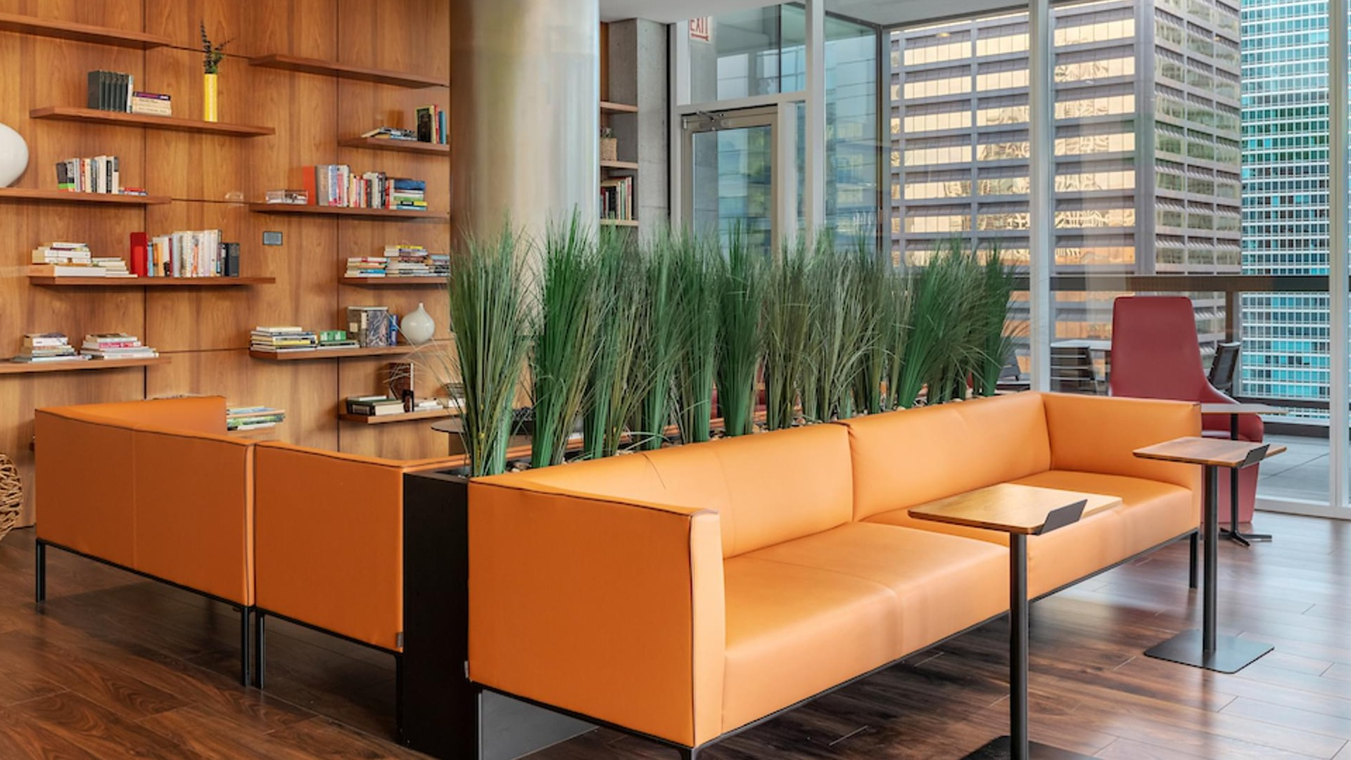 Resident lounge with orange leather sofas, indoor plants, and a central fireplace at Optima Signature apartments in downtown Chicago